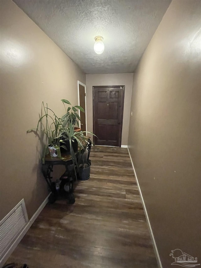 doorway with dark wood-type flooring and a textured ceiling