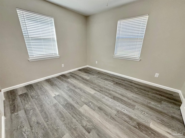 spare room with baseboards and wood finished floors