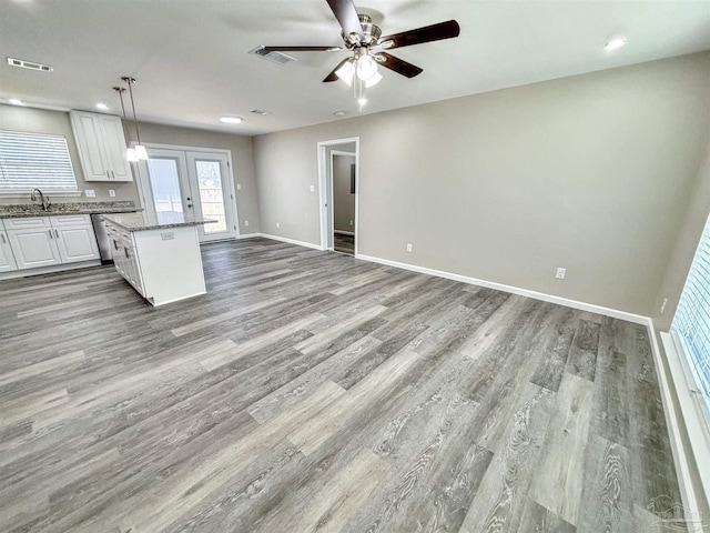 kitchen featuring a kitchen island, visible vents, white cabinets, open floor plan, and decorative light fixtures