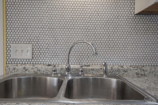 interior details with light stone counters, sink, and decorative backsplash