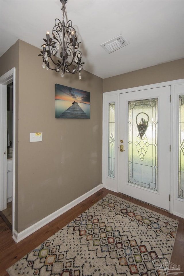 foyer entrance featuring dark wood-type flooring and a notable chandelier