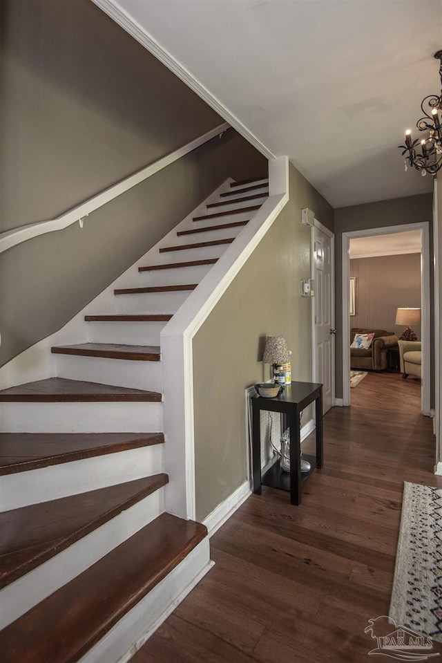 stairway with wood-type flooring and a chandelier