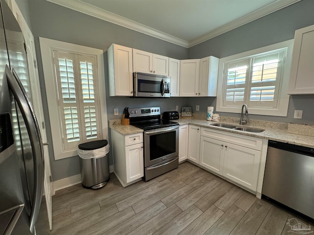 kitchen featuring light stone counters, stainless steel appliances, sink, white cabinets, and light hardwood / wood-style floors