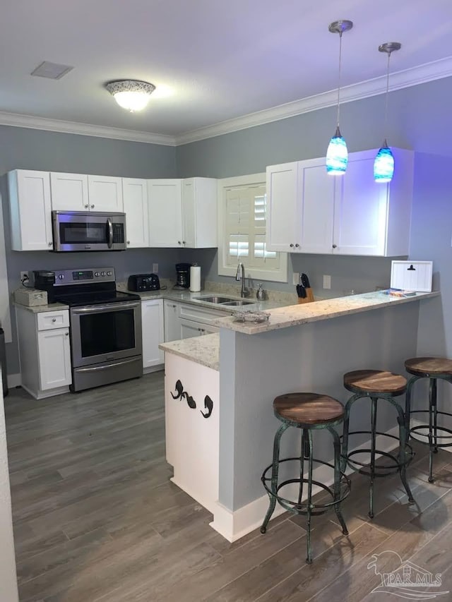 kitchen featuring a kitchen bar, kitchen peninsula, white cabinetry, and appliances with stainless steel finishes