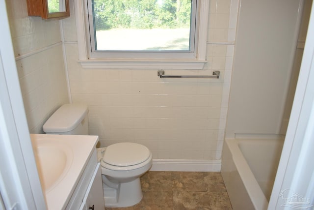 bathroom with tile patterned floors, a washtub, vanity, tile walls, and toilet