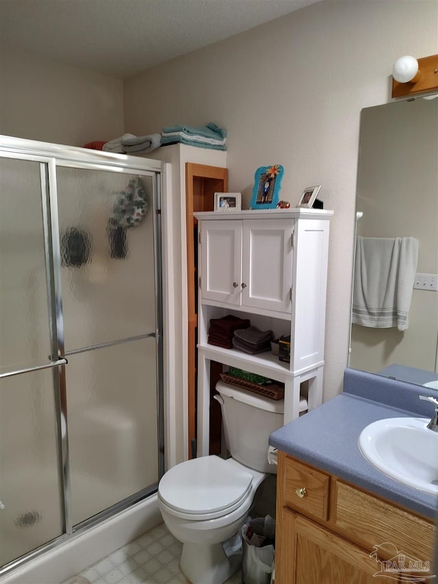 bathroom featuring a shower with door, vanity, a textured ceiling, and toilet