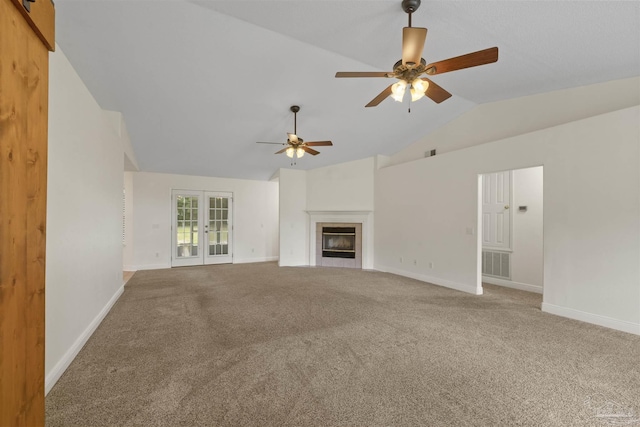 unfurnished living room with a ceiling fan, vaulted ceiling, carpet floors, baseboards, and a fireplace