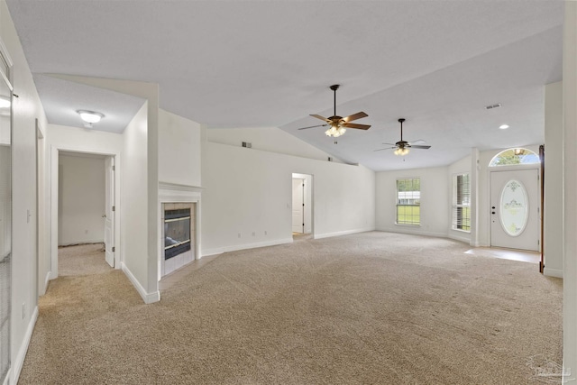unfurnished living room with light carpet, ceiling fan, baseboards, a tile fireplace, and vaulted ceiling