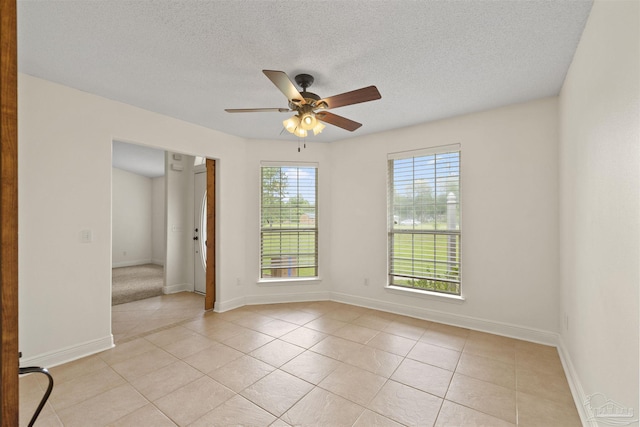 spare room with light tile patterned floors, a ceiling fan, baseboards, and a textured ceiling