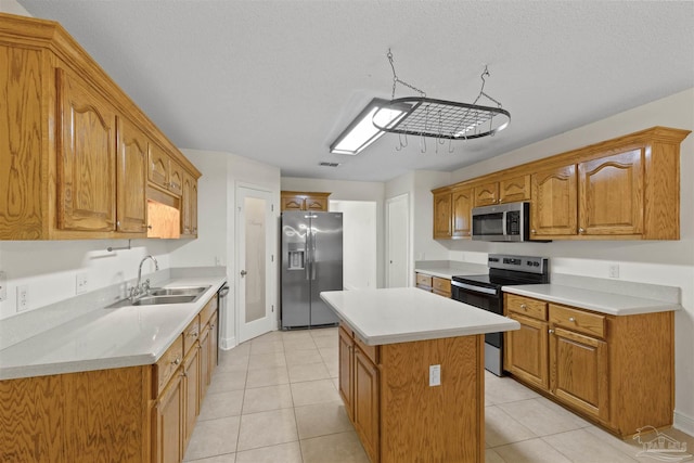 kitchen featuring stainless steel appliances, a sink, a center island, light countertops, and light tile patterned flooring