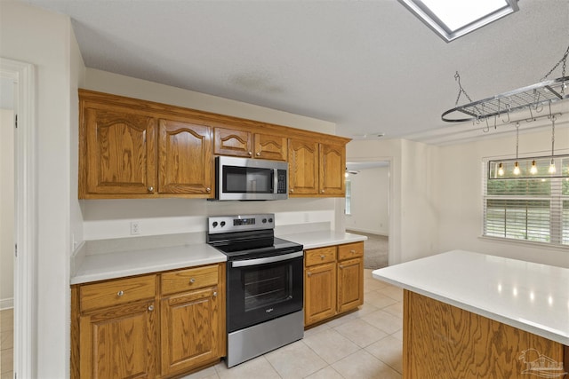 kitchen with appliances with stainless steel finishes, brown cabinets, light countertops, and light tile patterned flooring