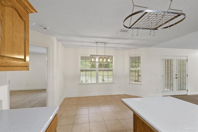 unfurnished dining area featuring a textured ceiling, light tile patterned floors, baseboards, and french doors