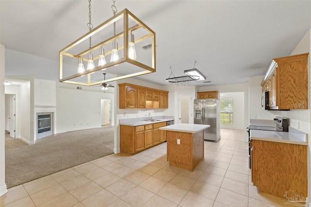 kitchen featuring appliances with stainless steel finishes, a sink, open floor plan, a kitchen island, and light countertops
