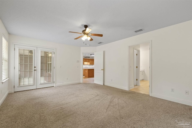 spare room with french doors, light colored carpet, a ceiling fan, and baseboards