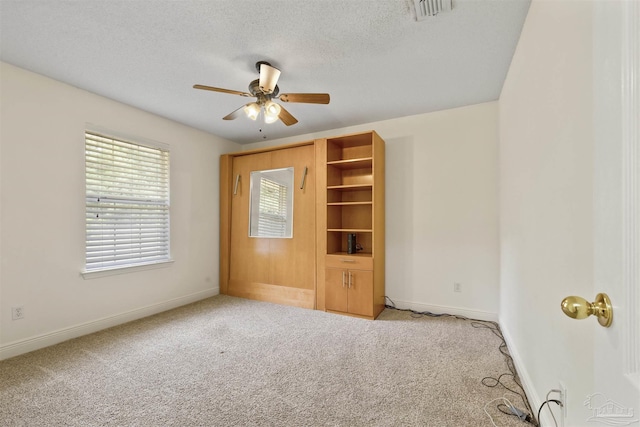 carpeted spare room with a ceiling fan, baseboards, and a textured ceiling