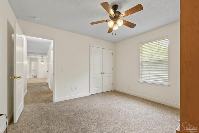unfurnished bedroom with carpet floors, baseboards, a closet, a textured ceiling, and ceiling fan