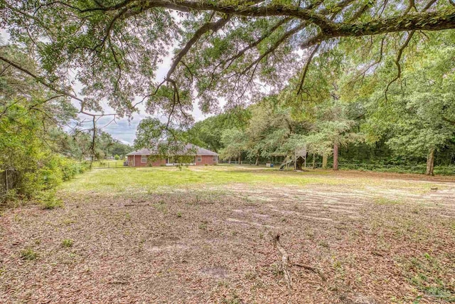 view of green lawn with a forest view