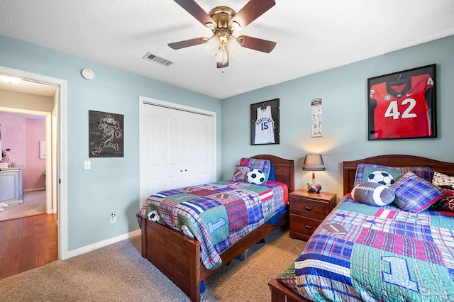 carpeted bedroom with a textured ceiling, ceiling fan, and a closet