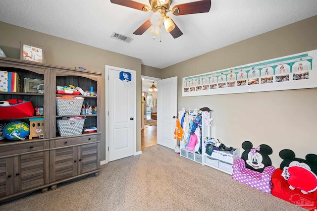 recreation room featuring carpet, ceiling fan, and a textured ceiling