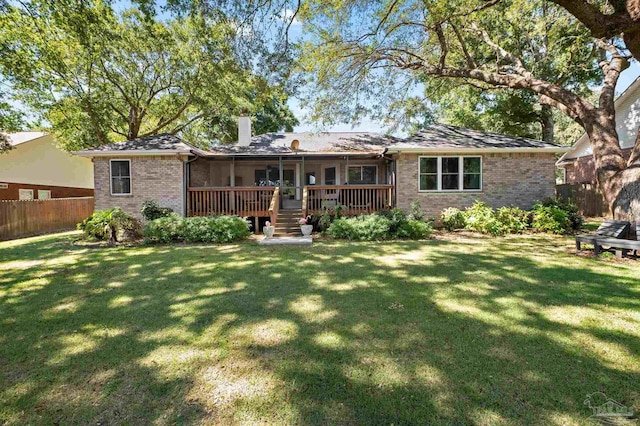 back of property with a wooden deck and a lawn