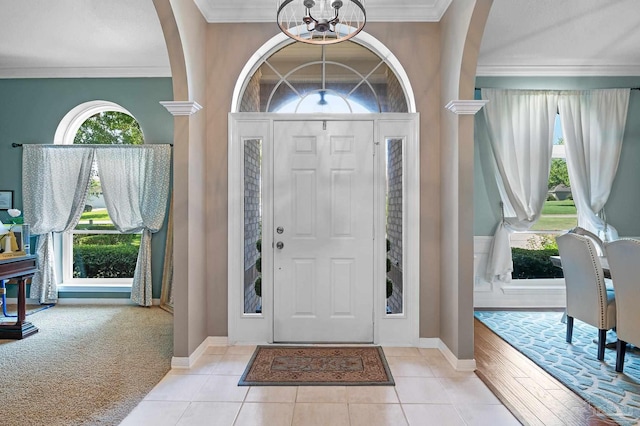 entryway with light tile patterned floors, an inviting chandelier, and ornamental molding