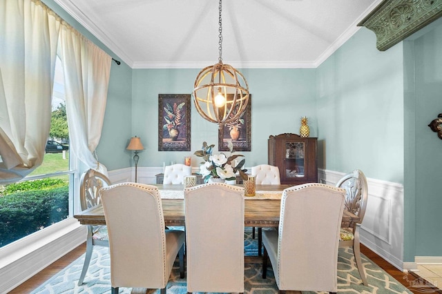 dining space with ornamental molding, hardwood / wood-style flooring, vaulted ceiling, and a chandelier