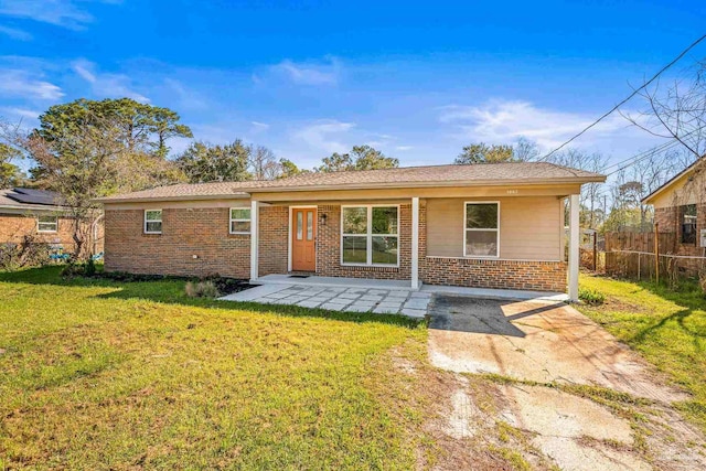 view of front of house with a front yard, a patio area, brick siding, and fence