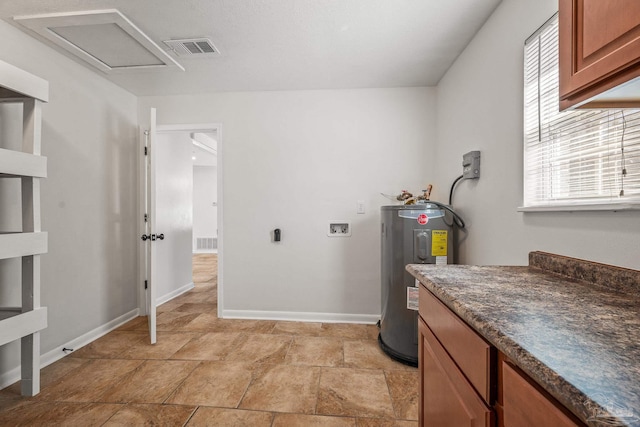 laundry room featuring water heater, washer hookup, visible vents, and baseboards