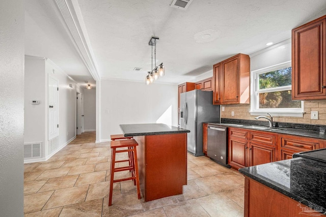 kitchen with visible vents, backsplash, appliances with stainless steel finishes, a sink, and a kitchen island