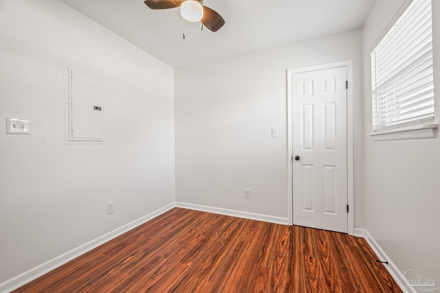 spare room featuring electric panel, ceiling fan, baseboards, and wood finished floors