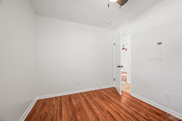 unfurnished room with a ceiling fan, wood finished floors, electric panel, and baseboards