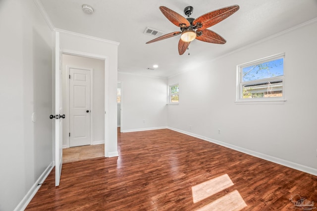 spare room featuring baseboards, wood finished floors, visible vents, and crown molding