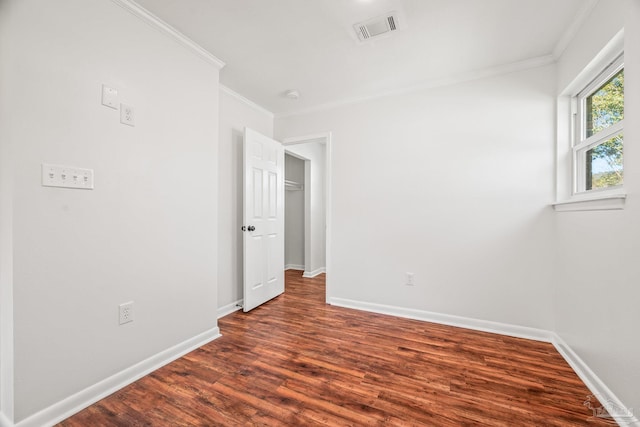 spare room with dark wood-style floors, baseboards, visible vents, and crown molding