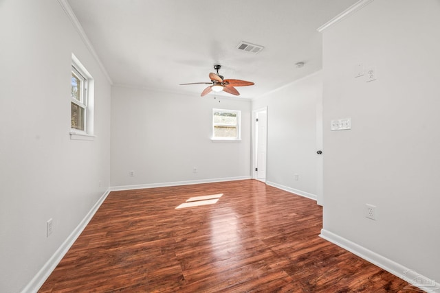 unfurnished room featuring ornamental molding, wood finished floors, visible vents, and baseboards