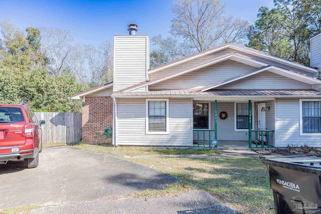 view of front of property with a porch, metal roof, fence, and a chimney