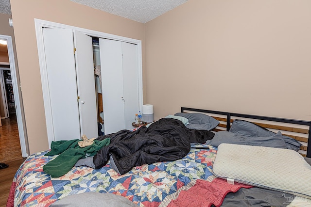 bedroom featuring a closet, a textured ceiling, and wood finished floors