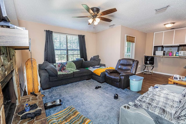 living room with visible vents, baseboards, wood finished floors, a textured ceiling, and a ceiling fan