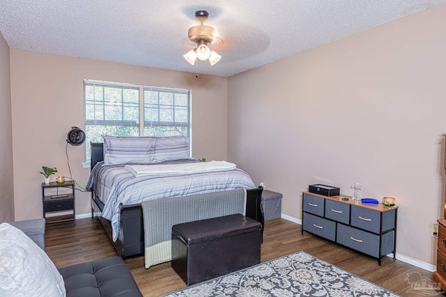 bedroom featuring baseboards, a textured ceiling, wood finished floors, and a ceiling fan