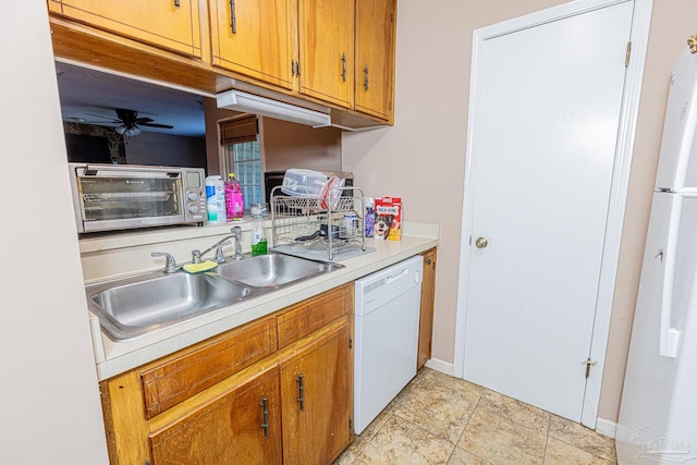 kitchen featuring ceiling fan, light countertops, brown cabinetry, white appliances, and a sink