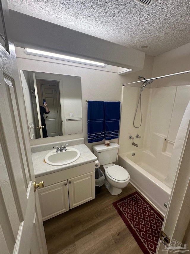 full bathroom with shower / bath combination, toilet, hardwood / wood-style floors, a textured ceiling, and vanity