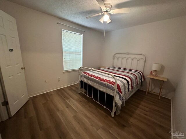 unfurnished bedroom with a textured ceiling, multiple windows, and dark hardwood / wood-style floors