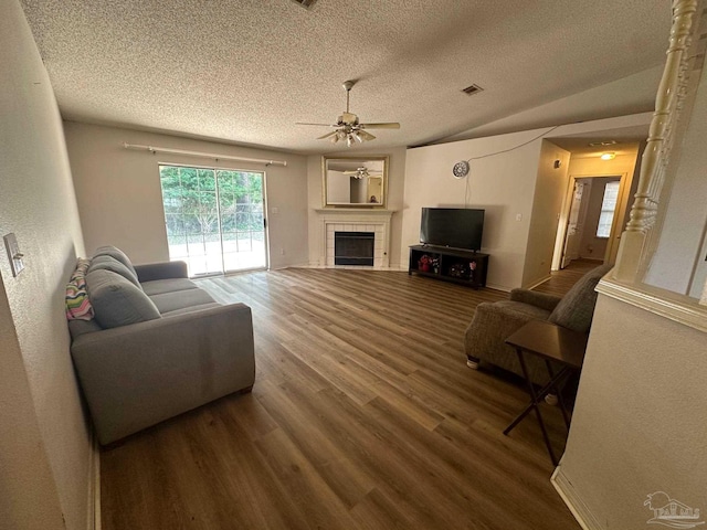 living room with a textured ceiling, hardwood / wood-style flooring, ceiling fan, and a tile fireplace