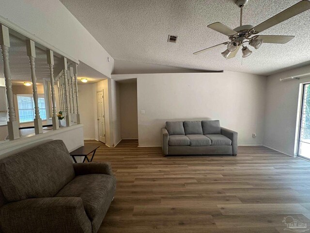 unfurnished living room featuring a tiled fireplace, ceiling fan, a textured ceiling, wood-type flooring, and vaulted ceiling