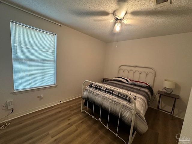 bedroom with dark wood-type flooring, multiple windows, a textured ceiling, and ceiling fan