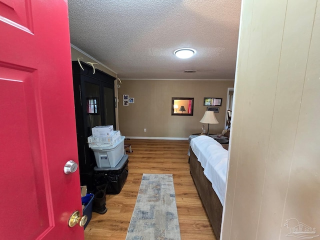 4940 Dawson Rd, Century, FL 32535 - bedroom featuring light wood-style flooring, a textured ceiling, ornamental molding, visible vents, and baseboards