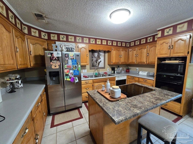 4940 Dawson Rd, Century, FL 32535 - kitchen with visible vents, black appliances, a breakfast bar, a sink, and brown cabinets