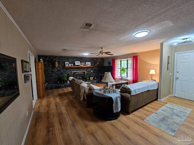 4940 Dawson Rd, Century, FL 32535 - living area with ceiling fan, a textured ceiling, visible vents, a stone fireplace, and wood finished floors