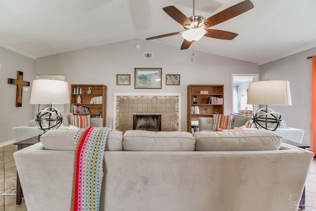 living room with light tile patterned floors, visible vents, a tiled fireplace, lofted ceiling, and ceiling fan