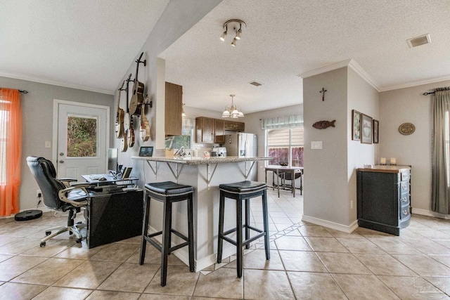 kitchen featuring a peninsula, a breakfast bar, visible vents, baseboards, and ornamental molding