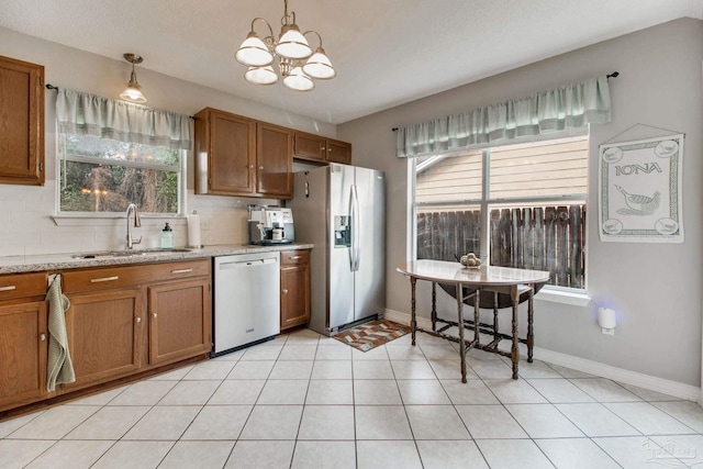 kitchen featuring appliances with stainless steel finishes, brown cabinetry, a sink, and decorative backsplash